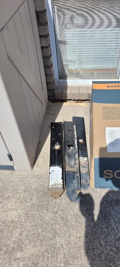 Three E-Z Menders extracted from one fence line, bent and paint-worn, lined up on the customer's walkway — Windsor, Ontario, May 2023.